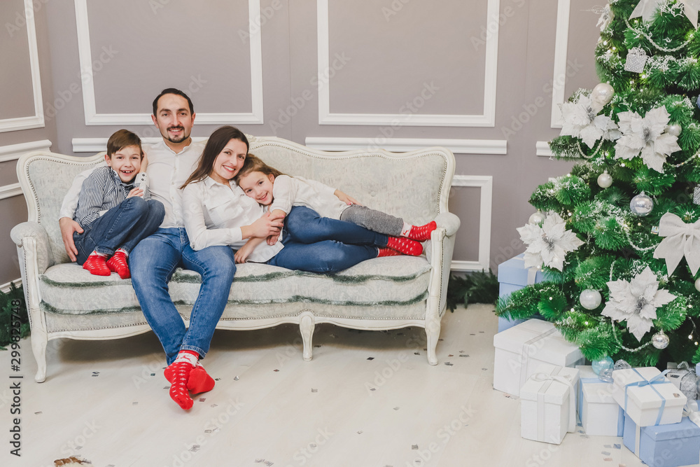 Loving parents and little children want to have photo near Christmas tree, they are posing and giving thumbs up. Loving parents and little children want to have photo near Christmas tree, they are posing and giving thumbs up.