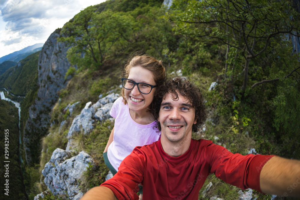 Couple taking a selfie against the backdrop of a mountain valley.