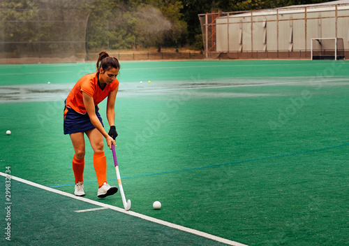 Female hockey player exercising on a grass field.