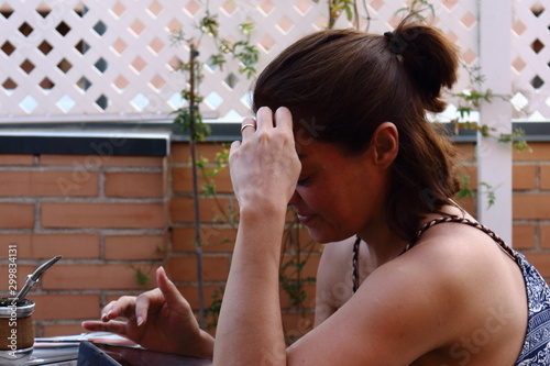 Mujer pensativa mirando una tablet mientras disfruta al aire libre de un mate caliente photo