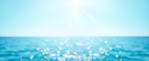 Beautiful Blur defocused blue sea background with sun rays and bokeh. Landscape of tropical summer. Summer vacation concept