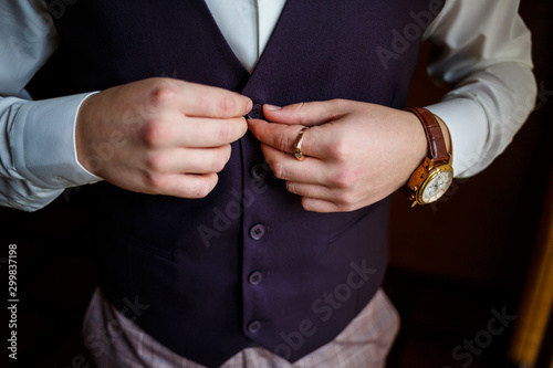 Man puts on a wedding suit and accessories on the wedding day.