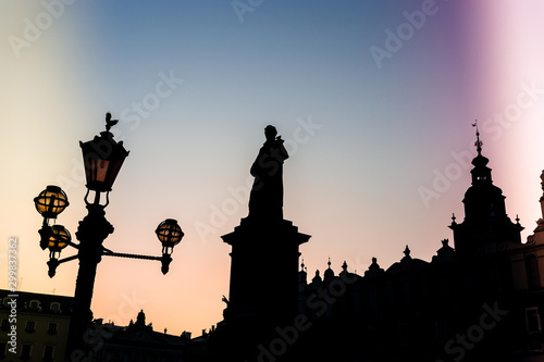 Silhouette of statue and townhall in Market Square during beautiful coloured sunset, Krakow, Poland. Light leak