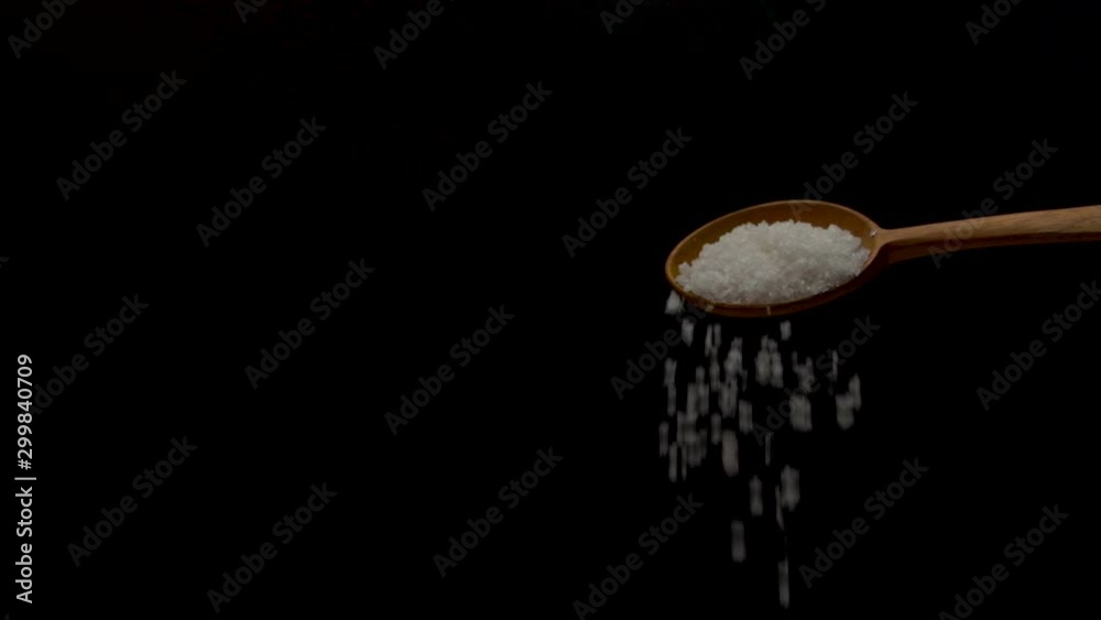 Grains of salt poured on with the help of a wooden spoon Grains of salt poured on with the help of a wooden spoon