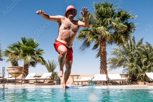 Overweight man jumping into swimming pool photo