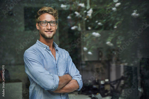 Portrait of casual young businessman behind windowpane in office