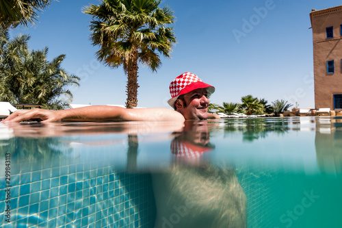 Overweight man with hat bathing in pool photo