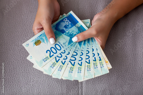 Photos Woman's two hands holding a fan of money of Israeli New Shekels