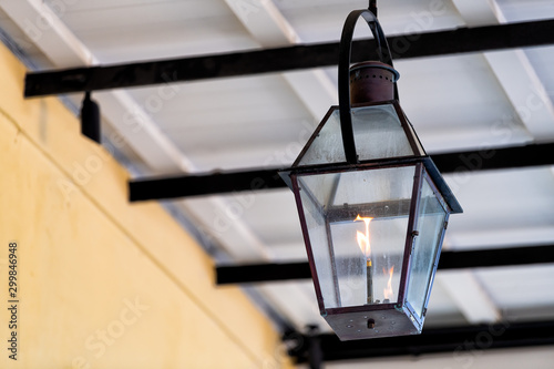Closeup of one gas lamp lanterns during day hanging on covered sidewalk street building as decoration in New Orleans, Louisiana photo
