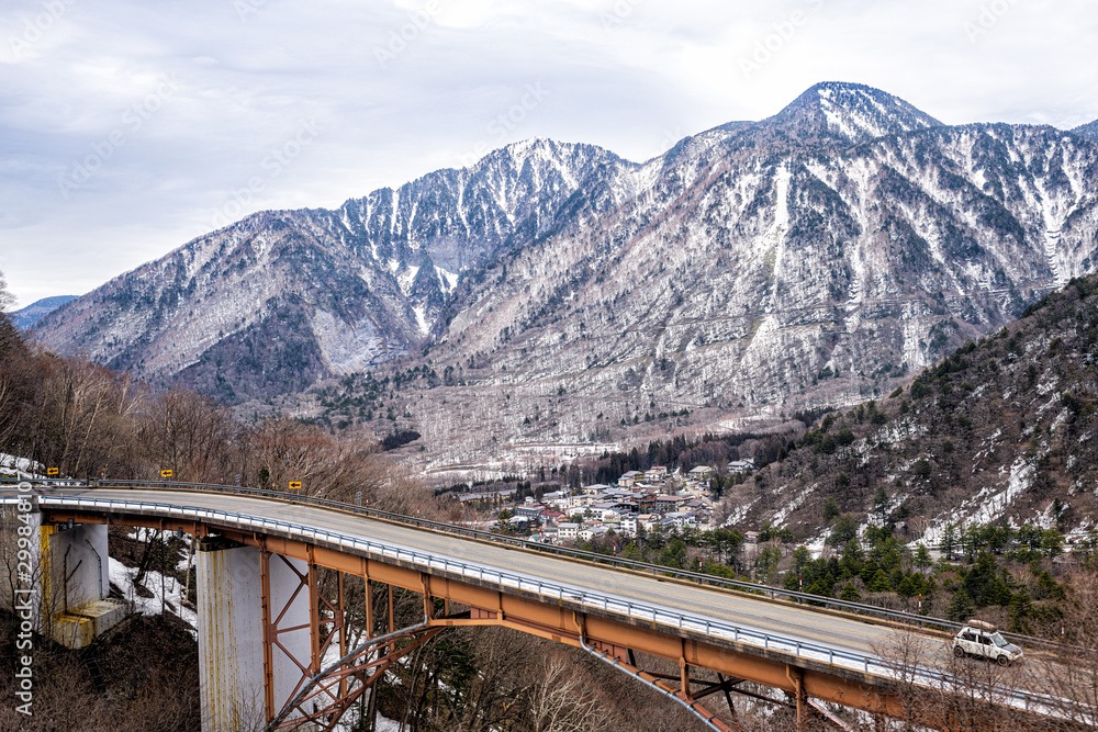 Takayama, Japan aerial high angle view of bridge and car on road in early spring in Gifu Prefecture Okuhida Villages near Shinhotaka Ropeway Takayama, Japan aerial high angle view of bridge and car on road in early spring in Gifu Prefecture Okuhida Villages near Shinhotaka Ropeway
