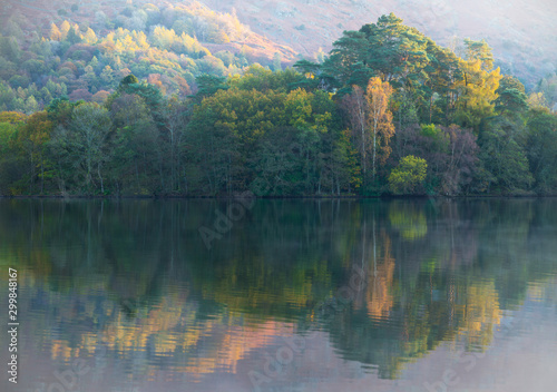 Trees change colour on the shores of Lake Grasmere in Autumn. UK