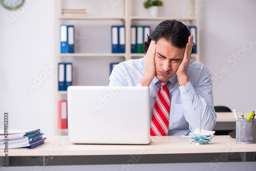Young male employee suffering in the office