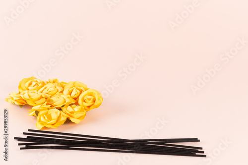 Black incense sticks with yellow flowers on pink background