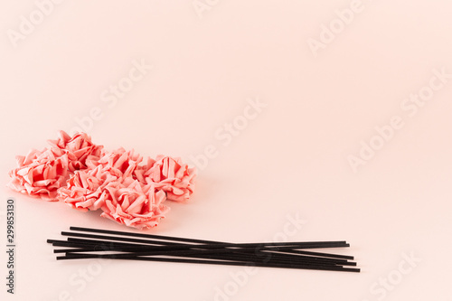 Black incense sticks with pink flowers on pink background