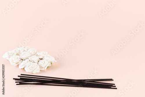 Black incense sticks with white flowers on pink background