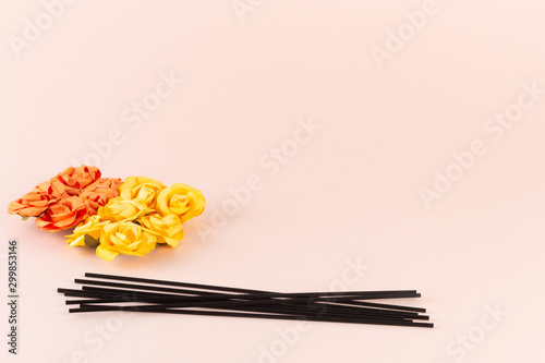 Black incense sticks with orange and yellow flowers on pink background