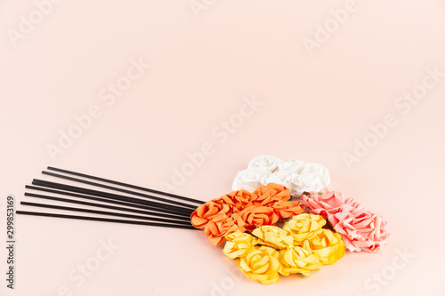 Black incense sticks with white, pink, orange and yellow flowers on pink background