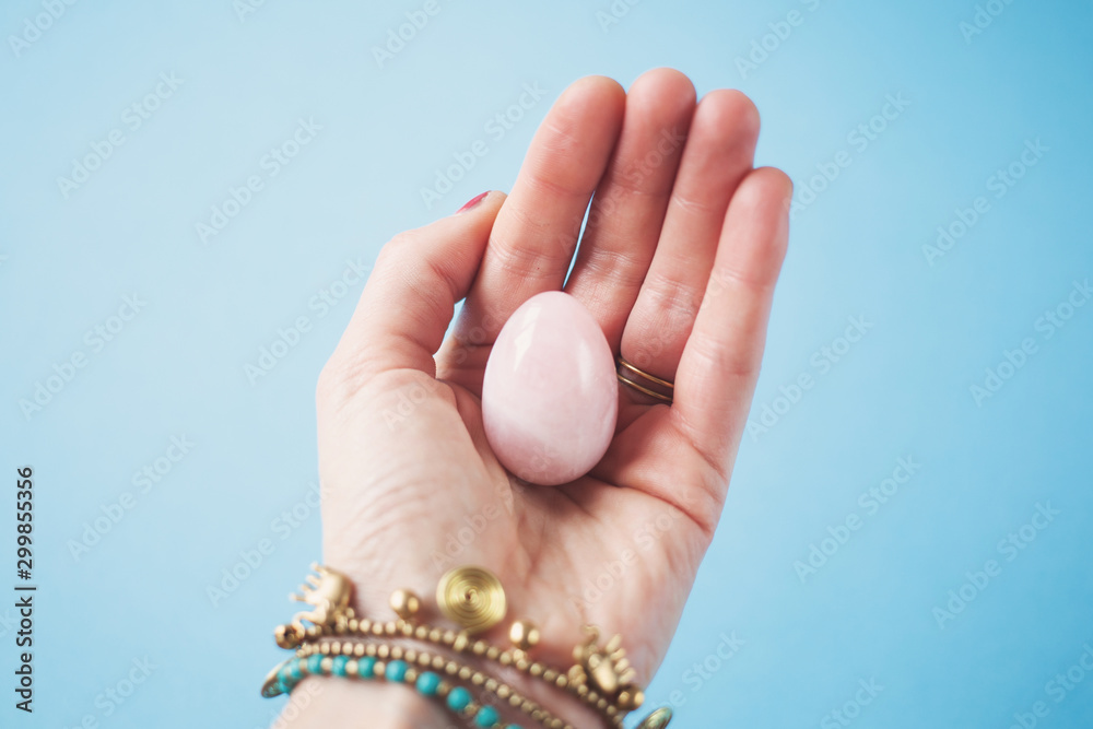 woman holding in hand a vaginal (yoni) egg. Rose quartz crystal jade egg. Copy space woman holding in hand a vaginal (yoni) egg. Rose quartz crystal jade egg. Copy space