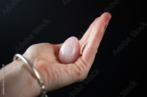 woman holding in hand a vaginal (yoni) egg. Rose quartz crystal jade egg. Copy space photo