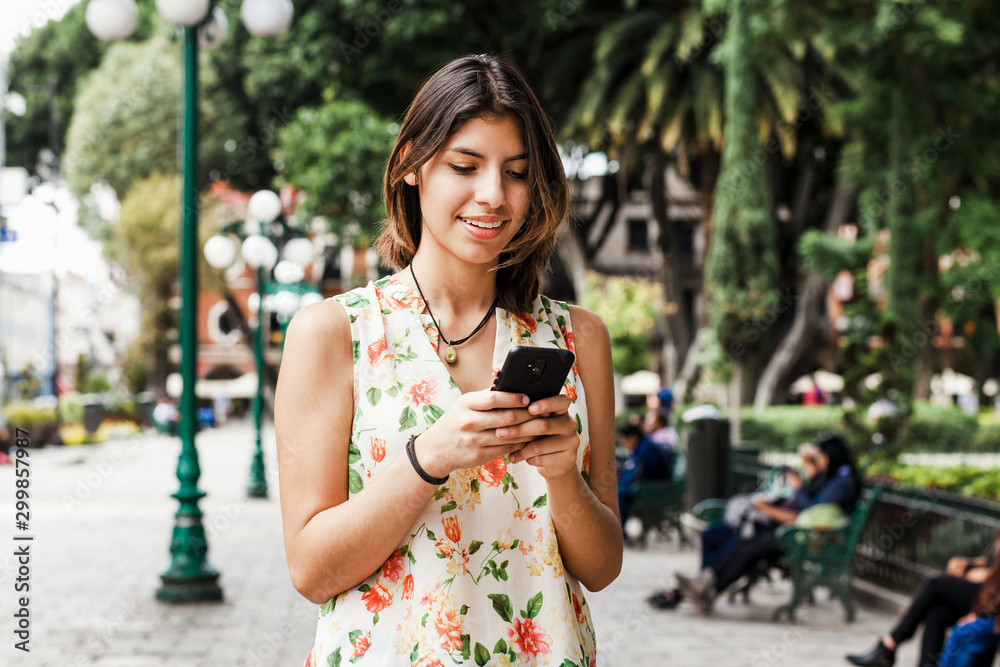 hispanic woman texting with her phone, Mexican beautiful woman in Mexico