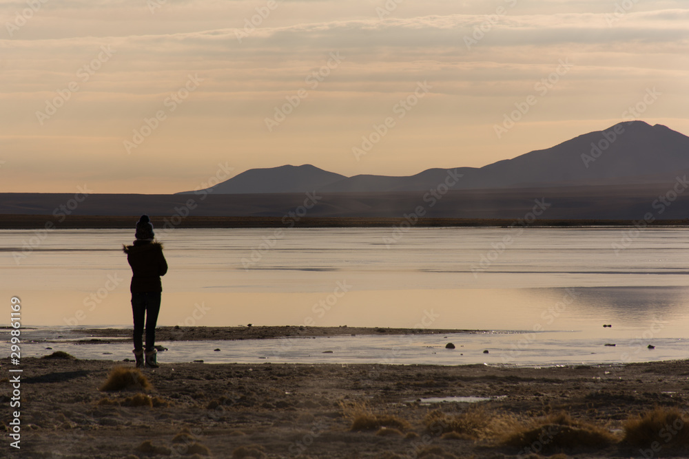 woman watching sunrise in the middle of clouds in middle of Amazing salt desert Andes Bolivian