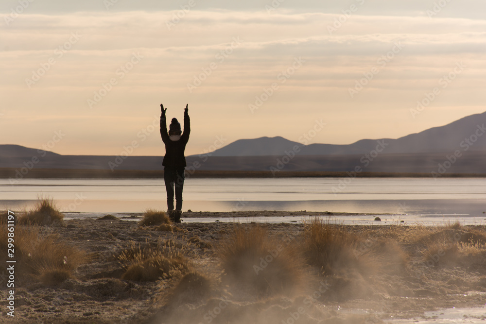 woman watching sunrise in the middle of clouds in middle of Amazing salt desert Andes Bolivian