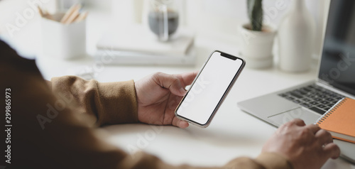 Cropped shot of young male freelancer holding blank screen smartphone