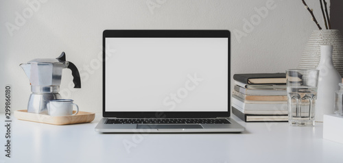 Modern workspace with open blank screen laptop computer with coffee cup and office supplies on white wooden table and white wall © bongkarn
