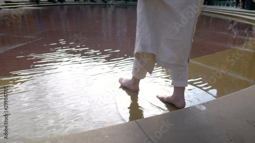 Slow motion: A woman walking on the water fountain in Victoria & Albert Museum in London, UK. Slow motion of her feet from the back. Shining water wave of John Madejski Garden 4K UHD photo