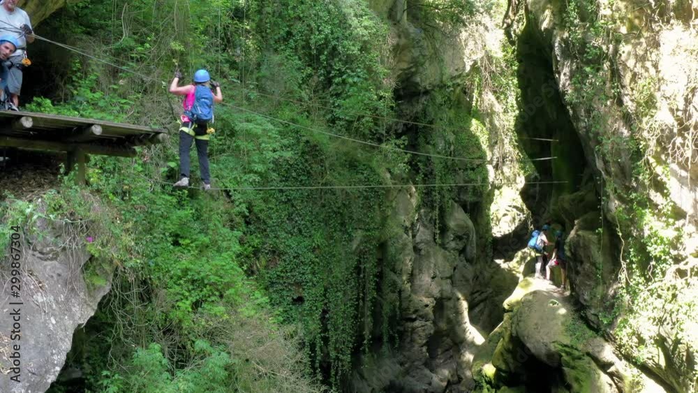 Woman performing adventure on rope in canyon at forest, people are enjoying vacation with sports activity - Alpes-Maritimes, France Woman performing adventure on rope in canyon at forest, people are enjoying vacation with sports activity - Alpes-Maritimes, France