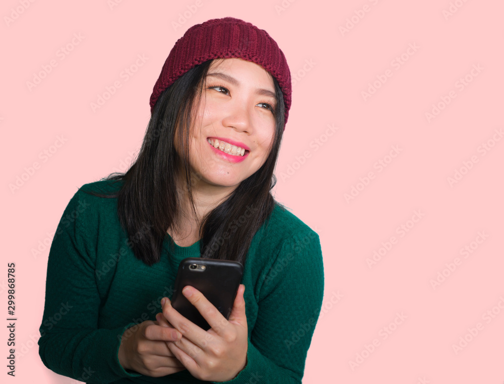 young beautiful and happy Asian Korean student woman using social media app on mobile phone enjoying excited and playful smiling sweet wearing winter hat isolated young beautiful and happy Asian Korean student woman using social media app on mobile phone enjoying excited and playful smiling sweet wearing winter hat isolated