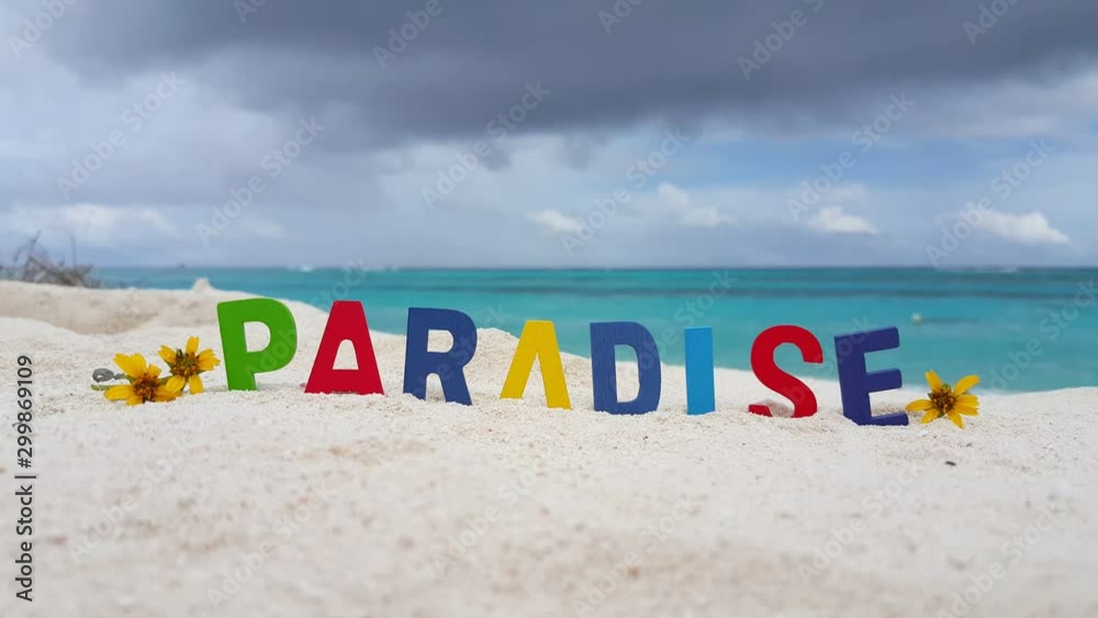 PARADISE word formed out of children toy wooden letters, decorated with small yelow flowers, creative background, tropical sandy beach PARADISE word formed out of children toy wooden letters, decorated with small yelow flowers, creative background, tropical sandy beach