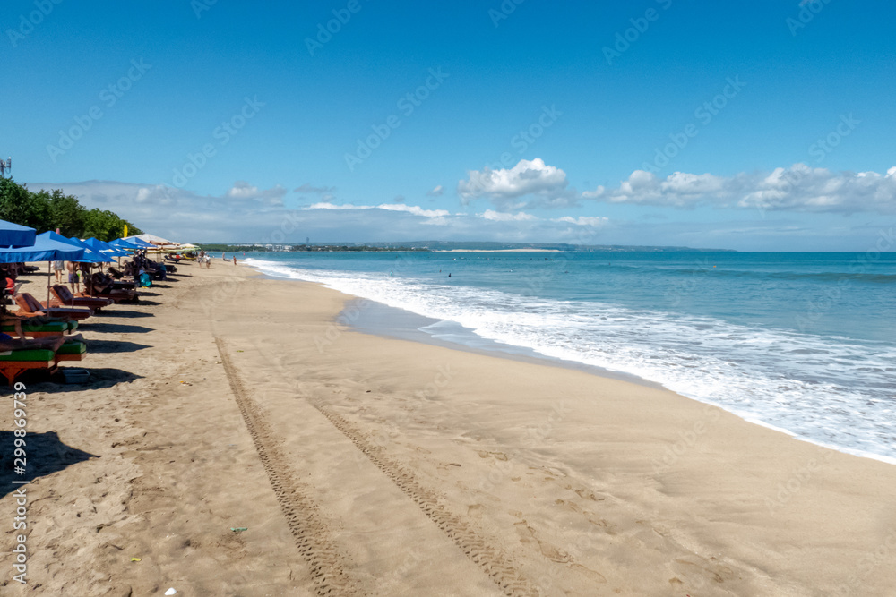 Long line of beach umbrellas on the beautiful calm Kuta beach in Bali