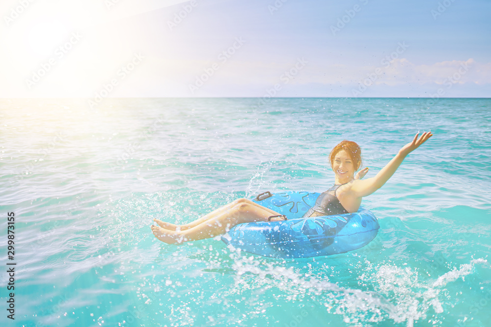 Amazing young woman relax on inflatable ring make water splash in sea water