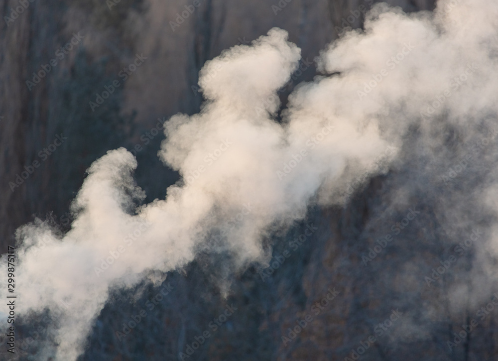 Smoke from the chimney of a house at dawn of the sun