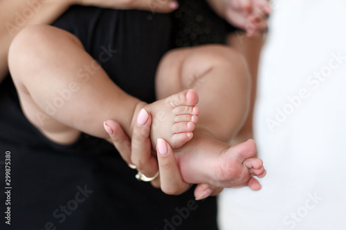 Baby feet in mother hands.Tiny Newborn Baby's feet on female hands closeup. Mom and Child.Mom doing gymnastics with kid.Happy Family concept. Beautiful conceptual image of Maternity.Mother doing exerc