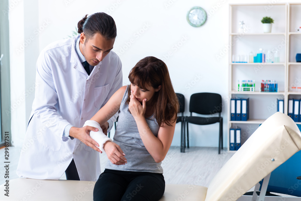 Fototapeta premium Young woman visiting male doctor traumatologist