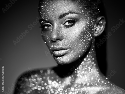 Fashion model woman in bright sparkles and lights posing in studio. Portrait ...