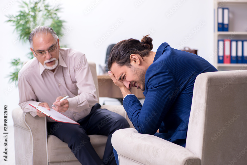 Young man visiting old male doctor psychologist