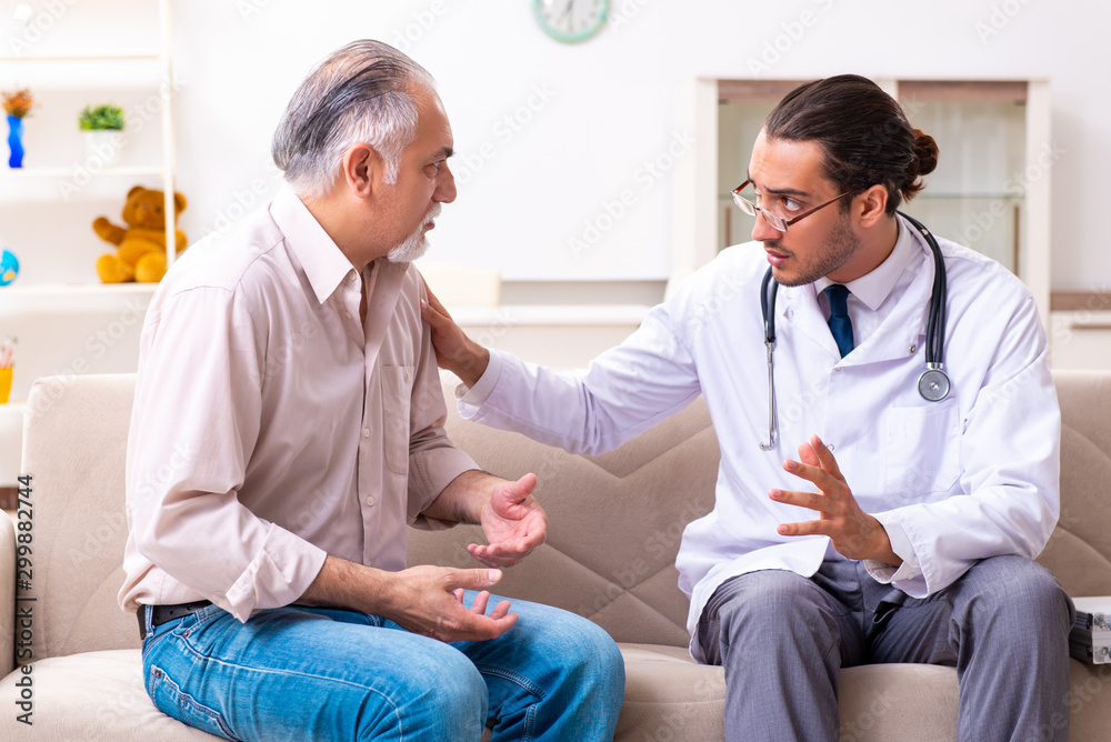 Young male doctor visiting old patient at home