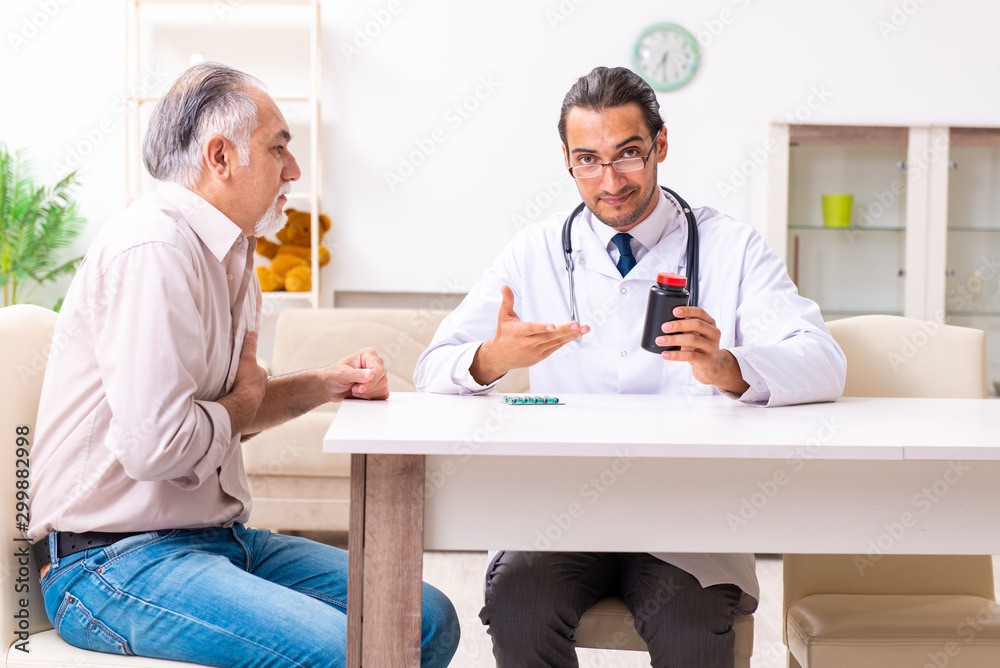 Fototapeta premium Young male doctor visiting old patient at home
