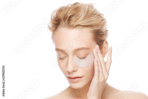 Young woman holding collagen eye patch with one hand, isollated on white background. Perfect clean fresh skin care treatment or cosmetic ads photo