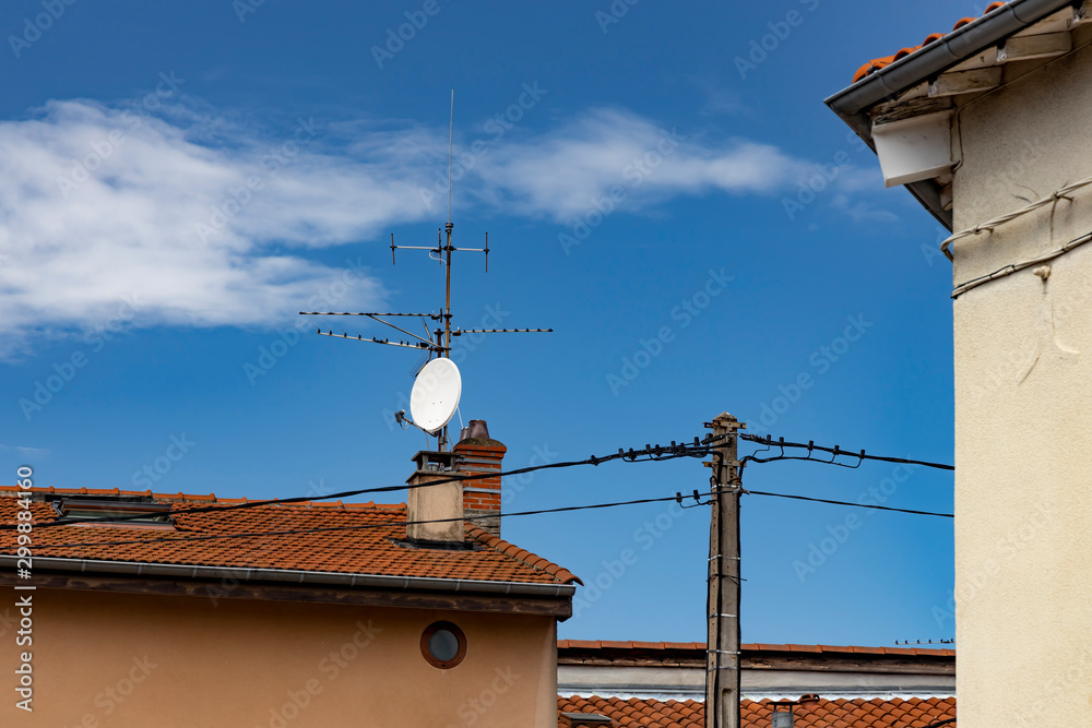 Satellite dish and TV antennas on the house roof. .Power pole.