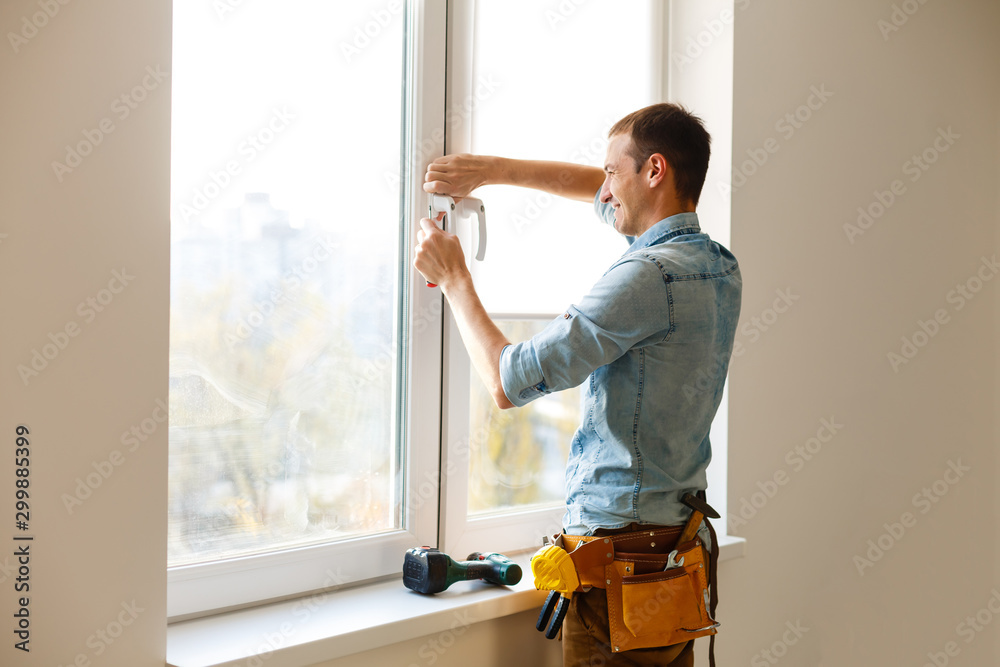 Man worker mounting window on balcony.