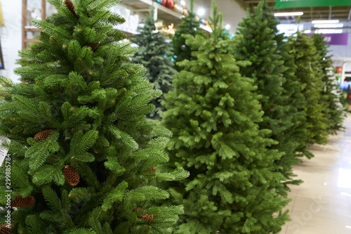 The sale of a variety of artificial Christmas trees of green color a range in the shop decor