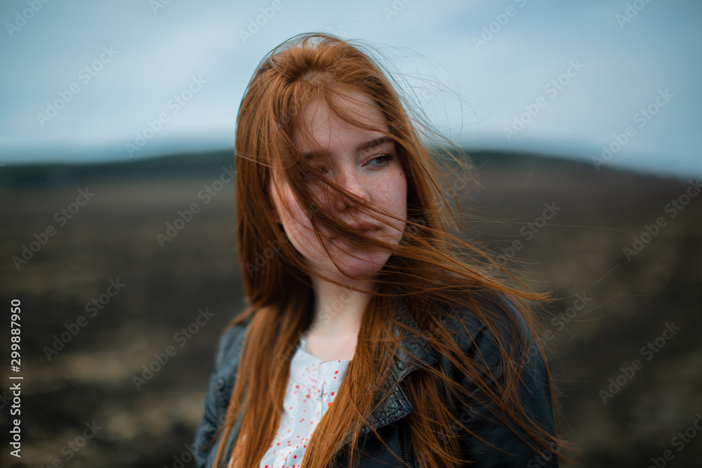 Long red hair covers the face of a young girl with freckles.