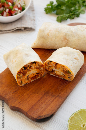 Homemade chorizo breakfast burritos on a rustic wooden board on a white wooden background, low angle view. Close-up.