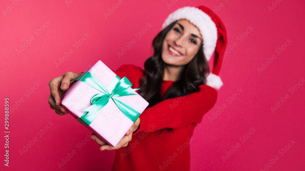 Giveaway. An appealing young lady in Christmas outfit is showing a gift, strapped with a green ribbon over the box and a nice bow at the top of it. Giveaway. An appealing young lady in Christmas outfit is showing a gift, strapped with a green ribbon over the box and a nice bow at the top of it.