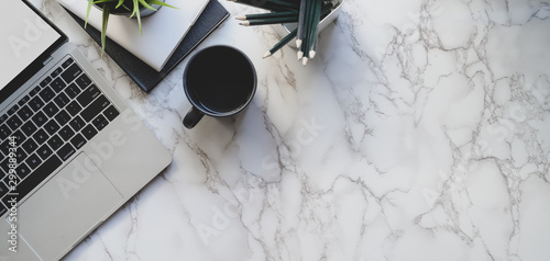 Top view of stylish workspace with laptop computer and office supplies on marble desk