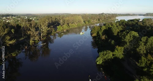 Aerial drone scene of fishing boat sailing along riverbend at foggy morning. Flying over water following boat from panoramic view of landscape to top view of ship. Rio Negro, Mercedes, Uruguay photo